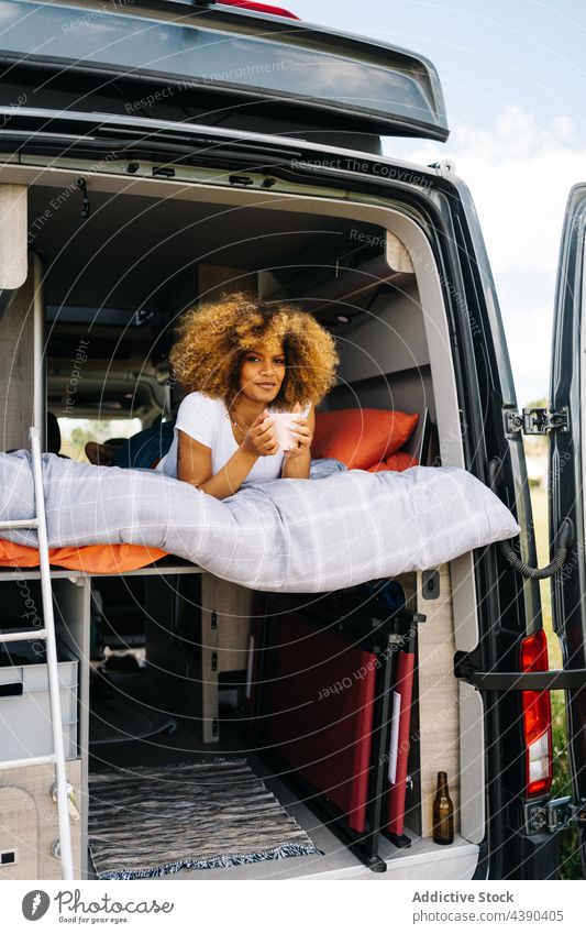 Black woman drinking hot beverage in caravan hot drink road trip bed harmony enjoy morning summer rest weekend female young coffee relax ethnic african american