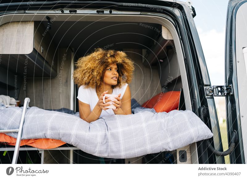 Black woman drinking hot beverage in caravan hot drink road trip bed harmony enjoy morning summer rest weekend female young coffee relax ethnic african american