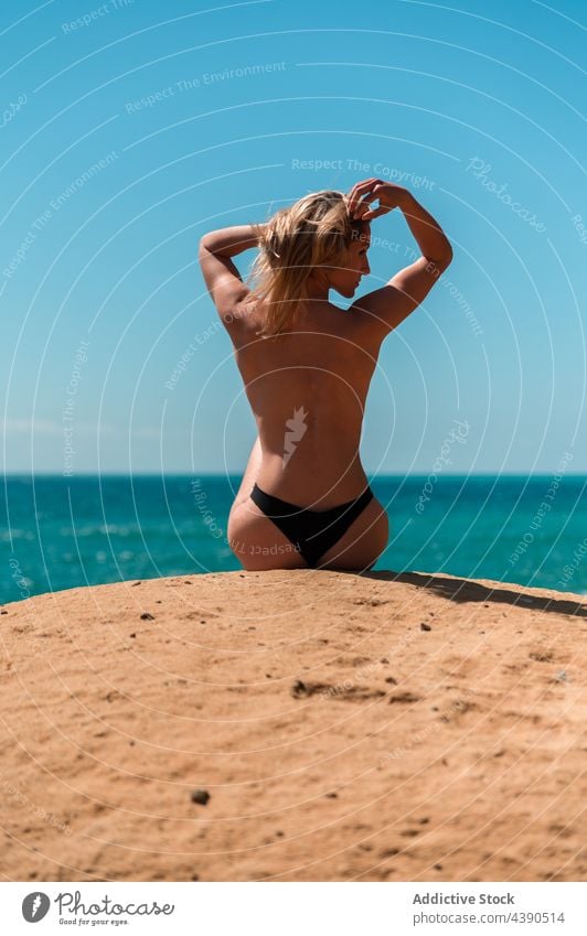 Anonymous woman sunbathing on rocky beach sea summer stone alone dreamy vacation female topless relax blond recreation travel freedom carefree calm tourism