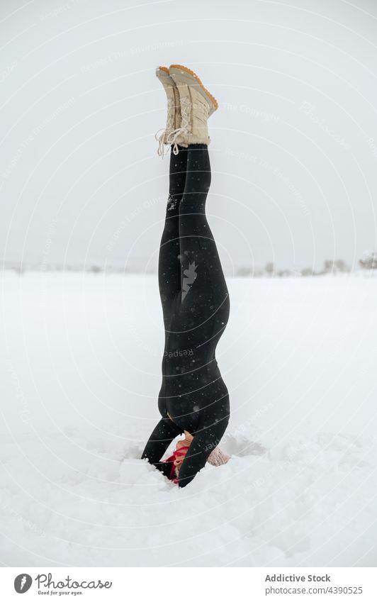 Woman practicing yoga in Supported Headstand pose in winter field woman headstand practice fit snow balance supported headstand pose female harmony healthy