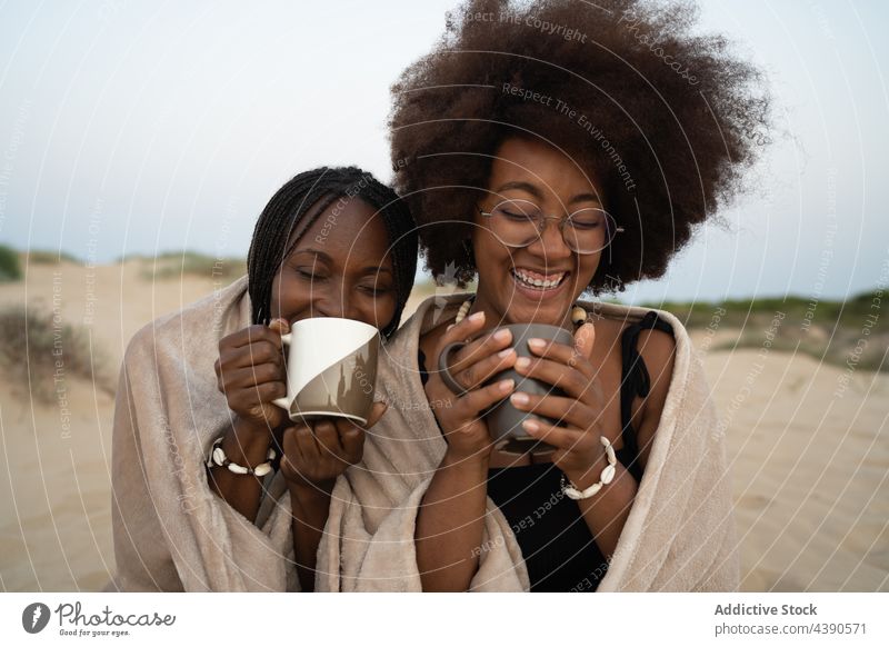 Cheerful black girlfriends drinking coffee on beach warm cheerful summer women happy together cup best friend vacation holiday young african american ethnic