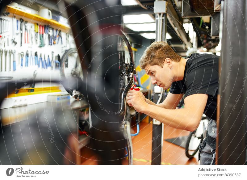 Focused mechanic pumping tire of bicycle in garage workshop gun man wheel inflate service male bike tool equipment professional job metal tyre repair occupation