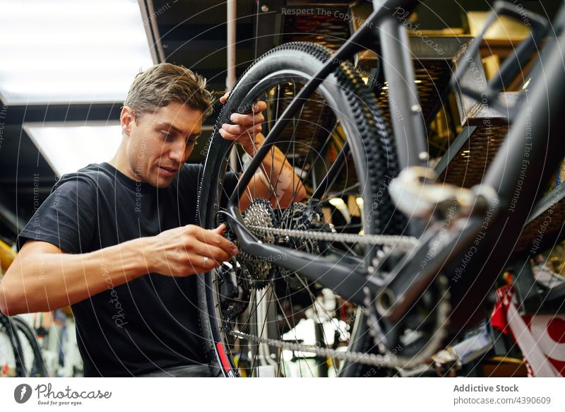 Man fixing bicycle wheel in garage man technician repair attach professional work service male adult cycling mechanic workshop maintenance repairman transport
