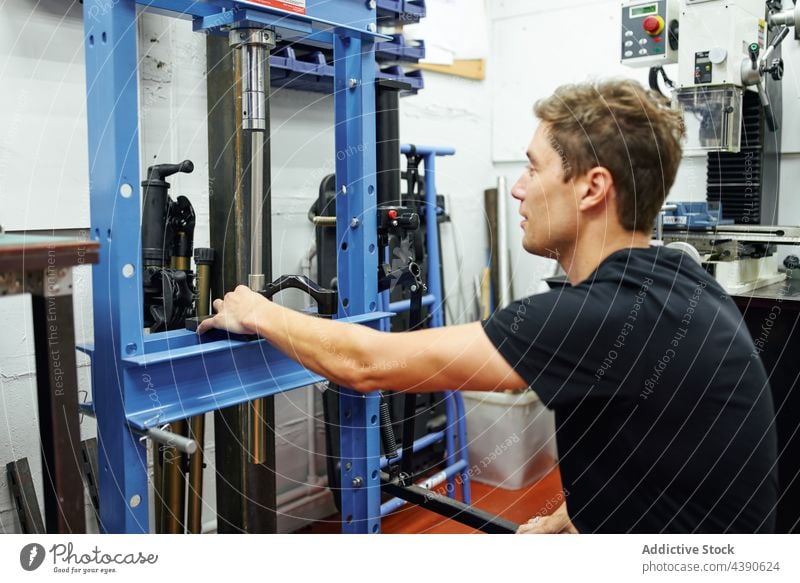 Male mechanic using hydraulic press man workshop repair professional occupation industry male small business adult equipment tool job skill manual maintenance