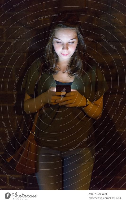 young woman uses mobile phone in the dark Cellphone using smartphone Light Flare Lighting Illuminate Technology Lifestyle Telephone Internet copywriting Screen