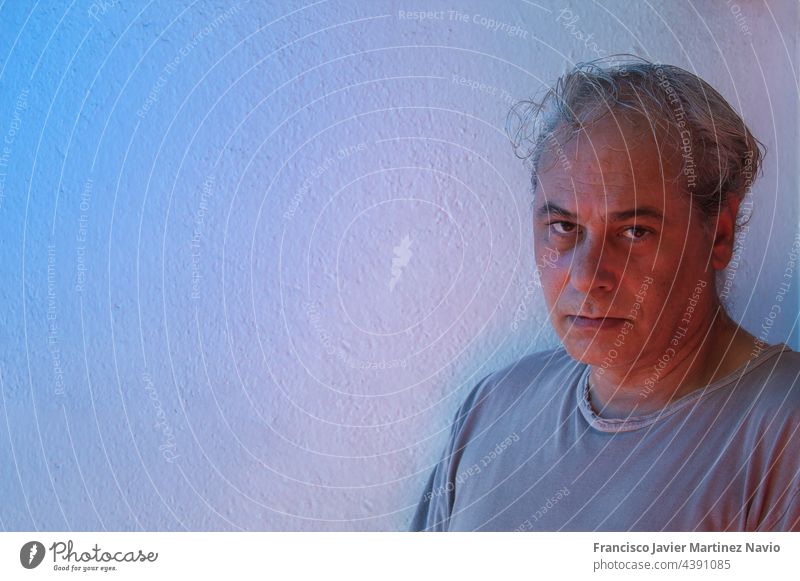 close-up with copy space of mature man with ambient color lights on a white background looking at camera expression spain screen 1 lonely house room mood