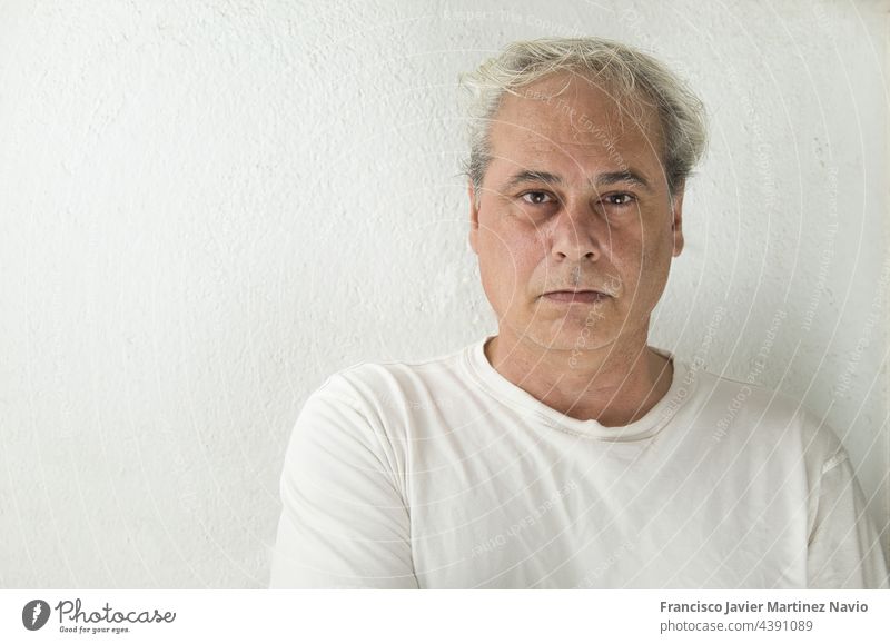 portrait of mature man with grey hair in white shirt on a white background looking at camera copy space adult close-up senior male person lifestyle people