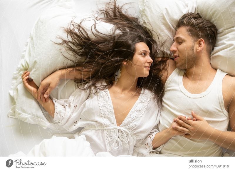 Top View of an romantic, attractive, contented, young, sexy loving couple in bed, copy space passion fun intimate intimacy laughing nightwear relaxing