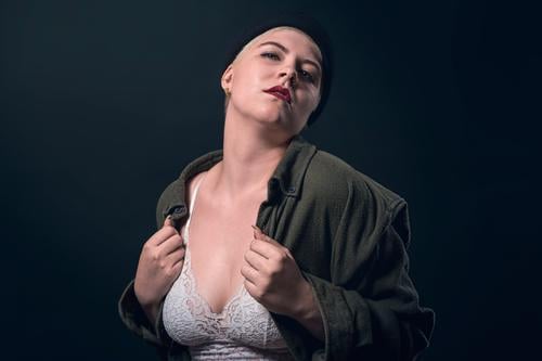 portrait of a young woman with a man's shirt, cap, and bustier studio confident heart love passion finger serious strong power powerful short hair business shy