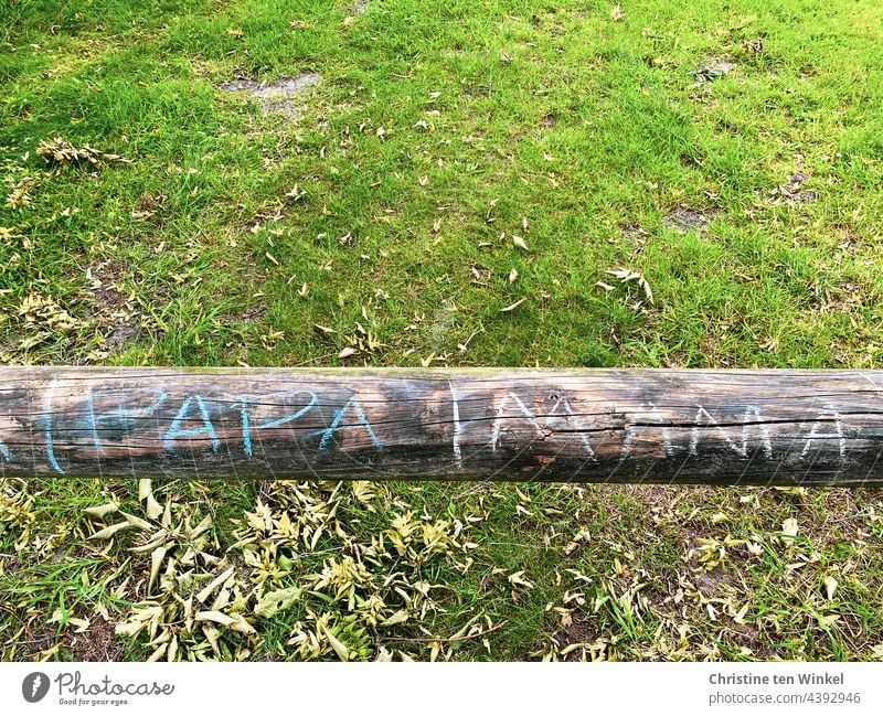 |PAPA|MAMA is written with coloured chalk on a round timber / wooden beam, which serves as a barrier in front of an empty lot mama dad chalk writing