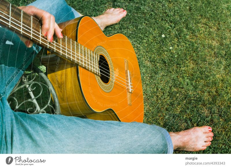 Music in the park. Guitar player plays on the lawn Guitar string Sound Close-up Make music Musical instrument string Wood Musician Leisure and hobbies Barefoot