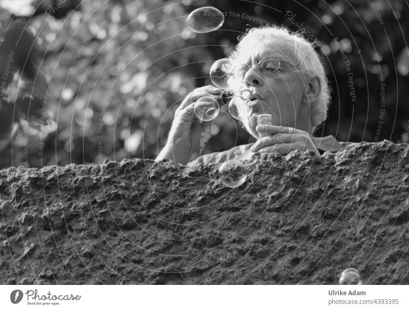 Parktour HH 2021 ------ Be a kid again ;-) Man makes soap bubbles Human being Adults be a child Playful blow Eyeglasses grey hair Black & white photo strained