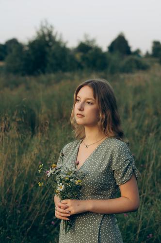 A young girl holds a bouquet of wildflowers in her hands. cottagecore aesthetics fresh air countryside slow life pastoral life caring sustainable vintage nature