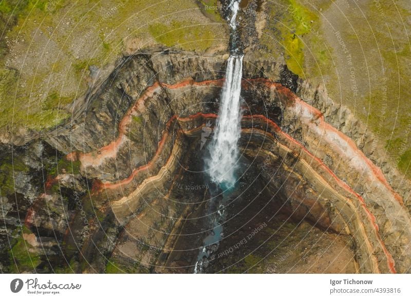 Aerial top down view of Hengifoss waterfall in East Iceland. The third highest waterfall in Iceland and is surrounded by basaltic strata with red layers of clay between the basaltic layers
