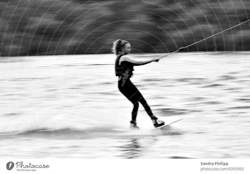 a girl is water skiing and the background is blurred Water ski Girl Sports Exterior shot Athletic Joy Summer Human being Youth (Young adults) Lifestyle workout