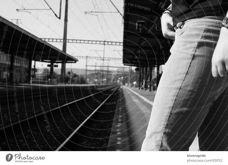 Just before Clock Cable Human being Woman Adults Hand Legs Train station Railroad Pants Line Stand Wait Black White Time Railroad tracks Risk Resolve Platform