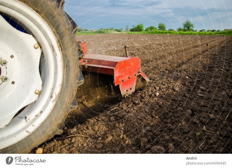 A tractor with a cutter unit is cultivating the field. Loose crushed moist soil after cultivating with a cultivator. Loosening surface, land cultivation. Farming. Use agricultural machinery