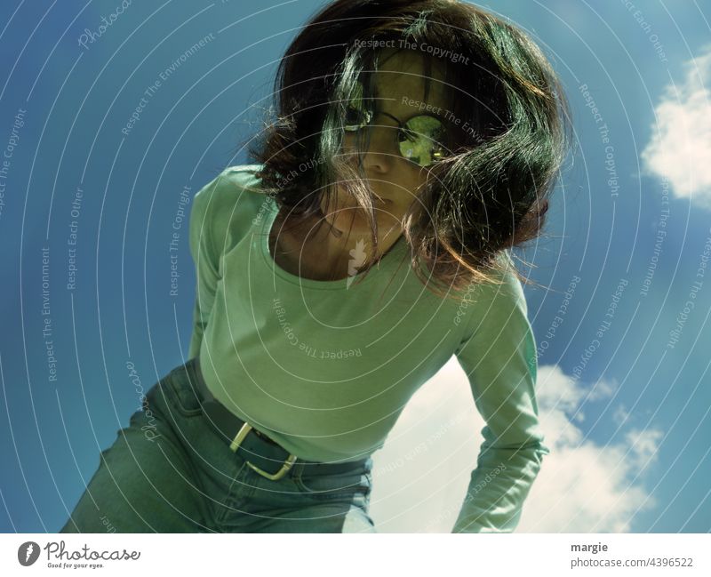 A woman in sunglasses looks down into the camera. Above her a blue sky with clouds Woman Young woman Hair and hairstyles Sky Face portrait Feminine Human being