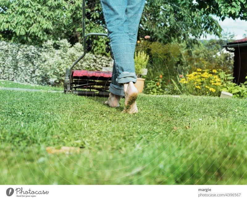 A woman barefoot mowing the lawn in the garden Lawn Mow the lawn Meadow Garden Gardening Feet Barefoot Lawnmower Grass mares Exterior shot Colour photo