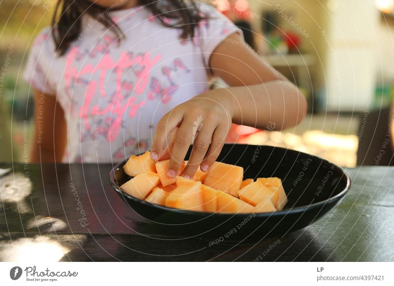 hand of a child grabbing a piece of melon from a black plate Family & Relations Infancy Child Education Parenting Leisure and hobbies Senses Contentment