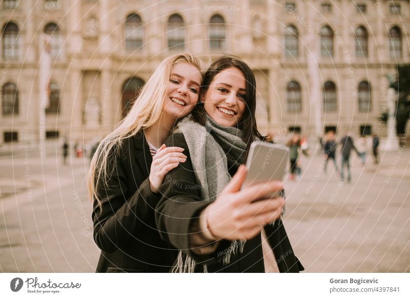 Young female tourists taking selfie with mobile photo in centre of Vienna, Austria ancient architecture austria beautiful building center city couple