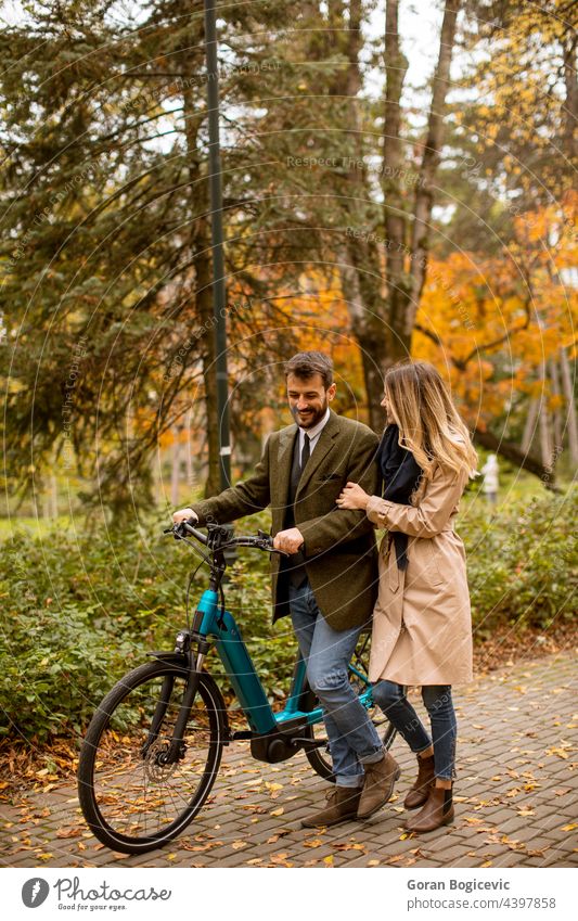 Young couple in the autumn park with electrical bicycle attractive autumnal beautiful boyfriend casual color date dating day e bicycle e bike ebike