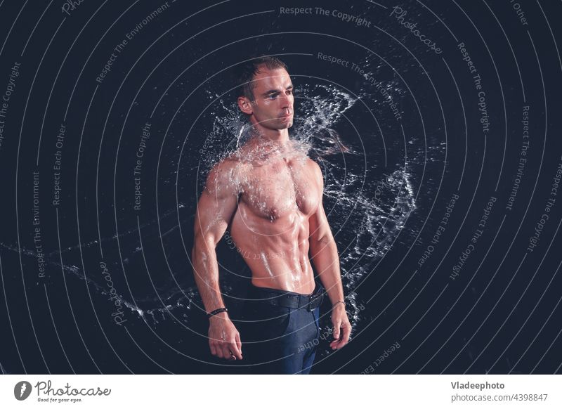 Muscular fitness man in wet clothes under rain with water splashes on dark background. aqua portrait abs fresh healthy muscular handsome fashion torso body