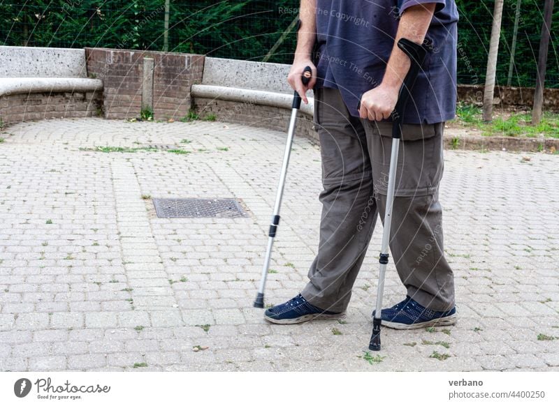 man walking with the aid of a pair of clutches pain senior health elderly copy space lifestyle people outdoor portrait summer disease illness insurance park