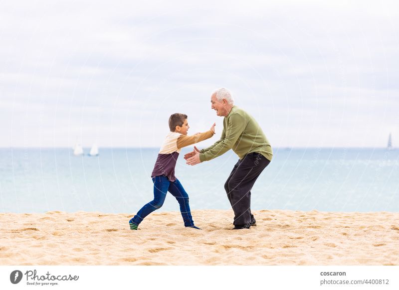 Happy boy running to hug his grandfather on the beach carefree cheerful child childhood children dad elderly family feel fun generation grandchildren