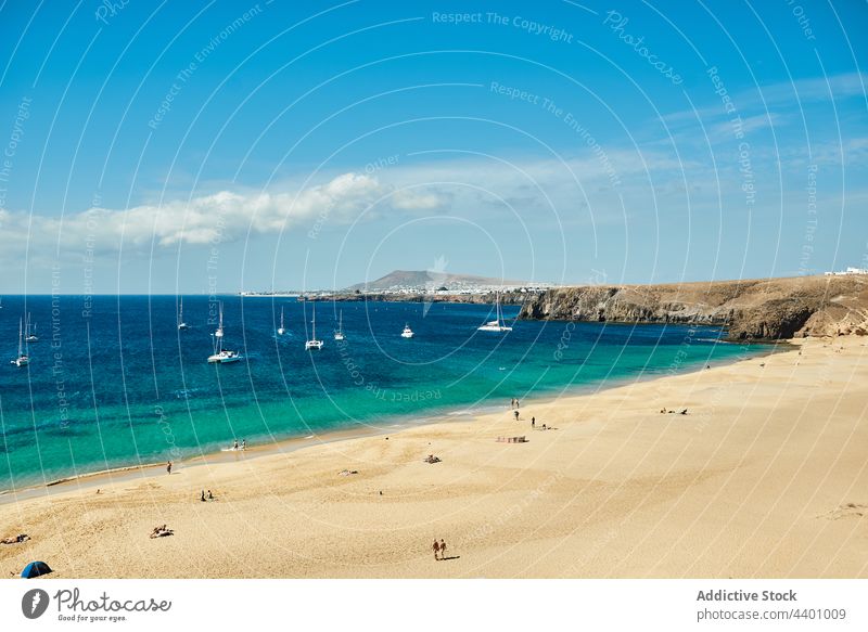 Beach with sailboats in the background sea shore summer blue sky water yacht nature rock daytime fuerteventura spain canary islands marine clean turquoise ocean