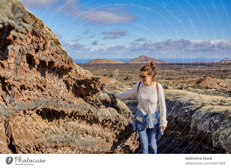 Female traveler touching rocky surface woman walk highland formation explore trip summer weekend fuerteventura spain volcanic canary islands nature stone