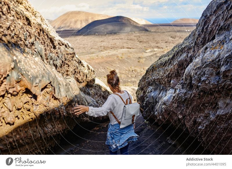 Female traveler touching rocky surface woman walk highland formation explore trip summer weekend fuerteventura spain volcanic canary islands nature stone