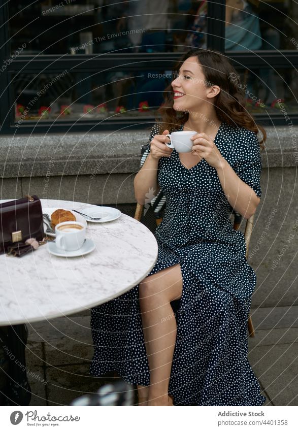 Stylish woman with latte in street cafe coffee hot drink beverage pastry dress legs crossed polka dot elegant style dotted ornament delicious aroma cappuccino