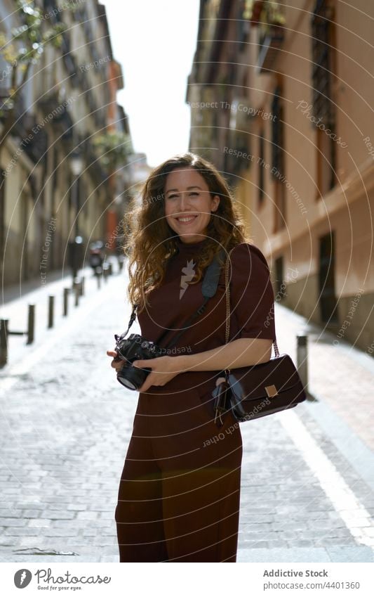 Cheerful photographer with digital photo camera on urban pavement cheerful contemplate sincere spare time street city woman content charming contemporary town