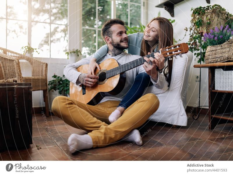 Smiling guitarist playing guitar while interacting with girlfriend at home relationship love music spend time house musical instrument classic acoustic string