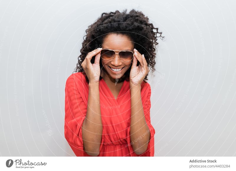 Fashionable black model in sunglasses on light background fashion trendy individuality feminine design curly hair woman portrait stylish creative style red wear