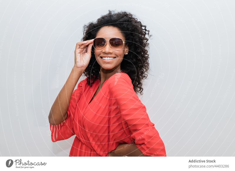 Fashionable black model in sunglasses on light background fashion trendy individuality feminine design curly hair woman portrait stylish creative style red wear