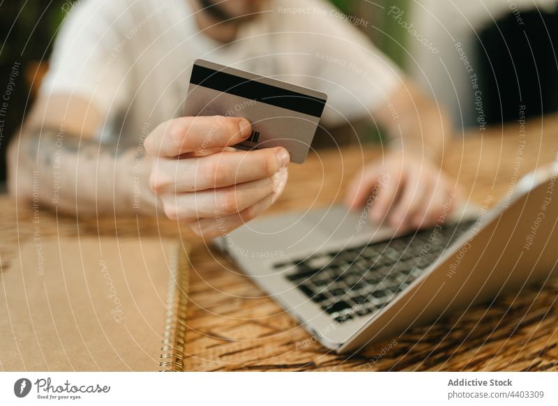Crop man making payment with plastic card during online shopping laptop purchase order shopper e commerce customer consume store buyer notebook transaction