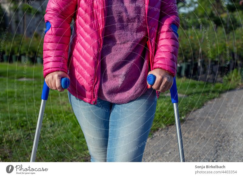 Woman on crutches after sports injury Crutches Walking aid Winter sports Sports injury Human being Exterior shot To go for a walk Colour photo Healthy Going