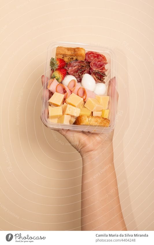 Hand holding lunch box with cheese, ham, bacon, salami and eggs. Set of gourmet snacks. appetizer background bread cuisine delicious diet eat food fresh health