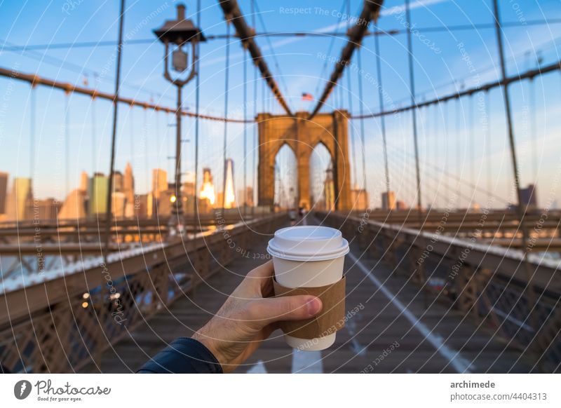 Man holding coffee cup in New York City take away hand in hand ny new york nyc drink city bridge street outdoors brooklyn brooklyn bridge lifestyle copy space