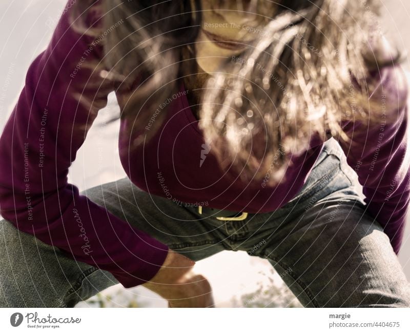 A woman sits in a crouch and looks into the camera (detail) Woman portrait Face Human being Hair and hairstyles long hairs Jeans excerpt portrait Crouch