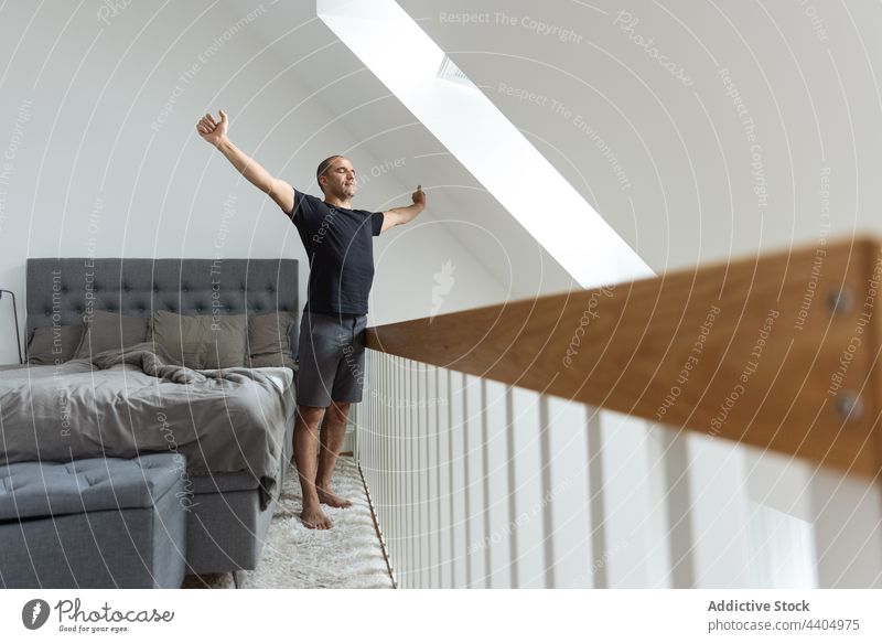 Man stretching after awakening in bedroom man morning home warm up wake up calm early male stand energy peaceful body tranquil domestic apartment comfort serene