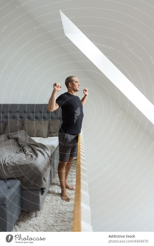 Man stretching after awakening in bedroom man morning home warm up wake up calm early male stand energy peaceful body tranquil domestic apartment comfort serene