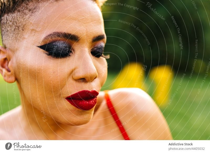 Stylish black woman with makeup portrait closed eyes individuality confident haircut park style festive wear red color bright african american modern ethnic
