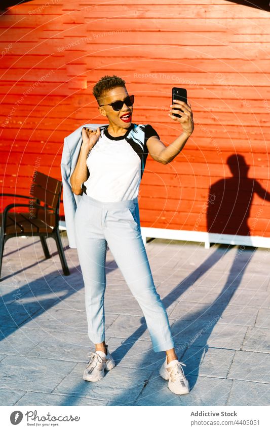 Stylish black woman in sunglasses speaking on smartphone on street fashion stylish individuality hand in pocket cool using gadget device style pavement