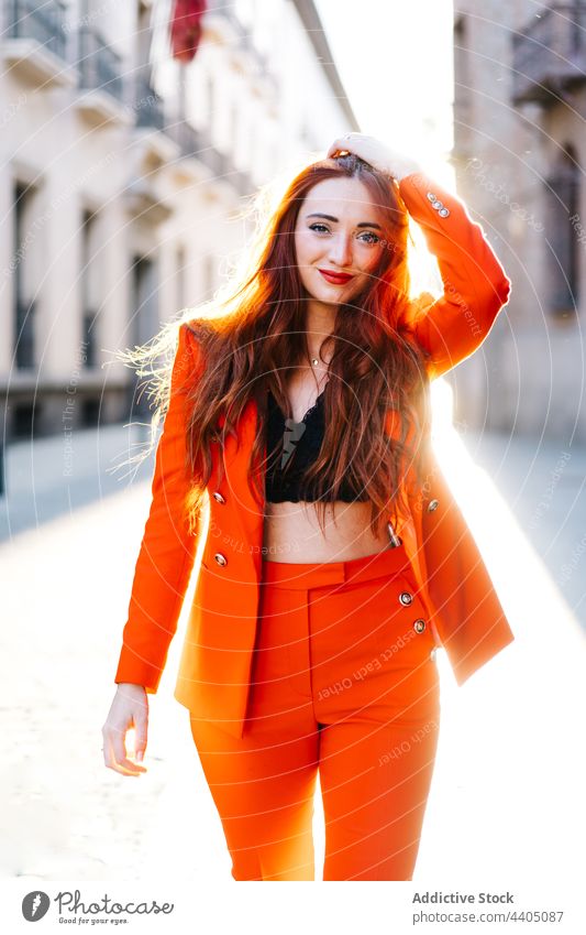 Trendy redhead woman in suit in city orange bright vivid street style trendy female outfit confident urban fashion building modern model contemporary