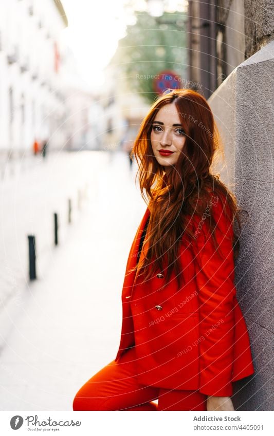 Trendy redhead woman in suit in city orange bright vivid street style trendy female outfit confident urban fashion wall lean building modern model contemporary