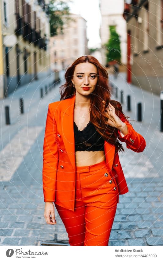 Redhead woman in orange suit in city street style trendy bright color walk redhead female outfit fashion confident appearance urban serious model determine