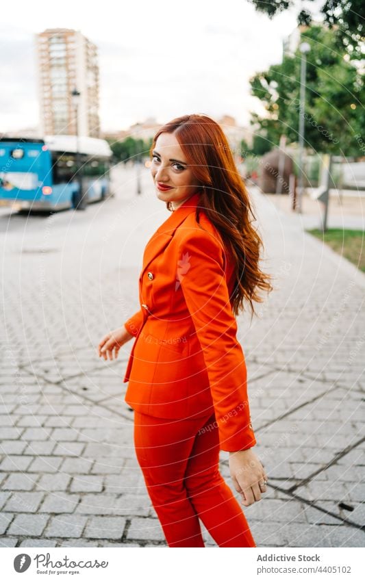 Trendy redhead woman walking in the city street cross road suit vivid style ginger female fashion confident trendy long hair contemporary outfit appearance